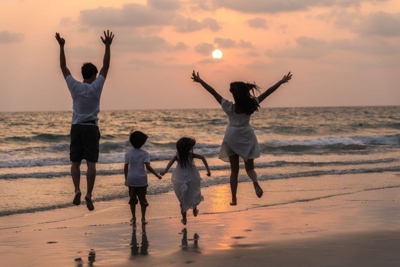 Familia feliz disfrutar de vacaciones en la playa en la noche papá mamá y el niño relajarse corriendo juntos cerca del mar