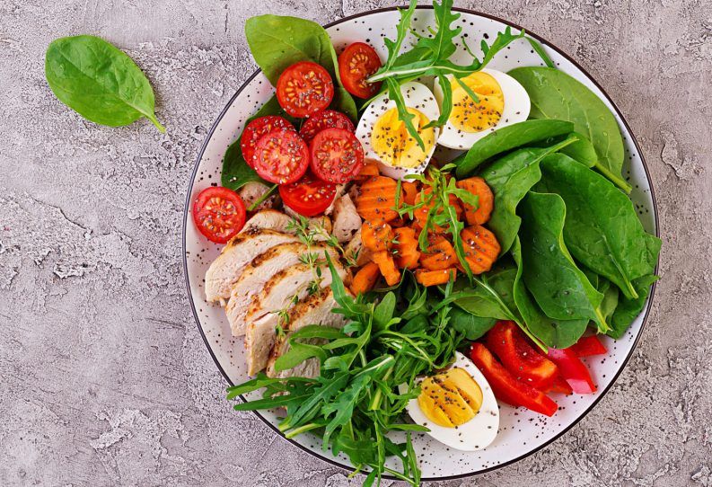 Plato con cerezas, tomates, pollo, huevos, ensalada de zanahoria con arugula y espinaca