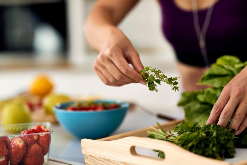 primer plano mujer usando perejil mientras prepara alimentos saludables cocina